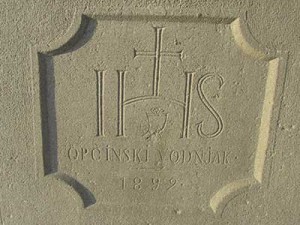 IHS: Monogram je krščanski simbol, ki prikazuje prve tri črke grške pisave imena Jezus, ΙHΣOYΣ. Napis: Opčinski vodnjak, 1899